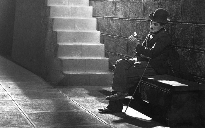 Charlie Chaplin sitting with a flower