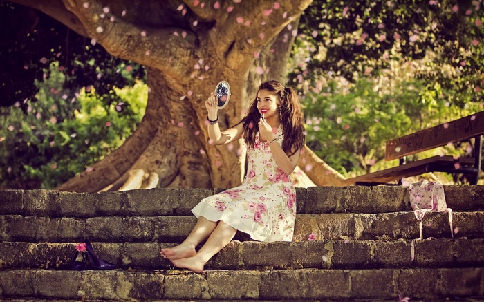 Girl applying makeup under a tree