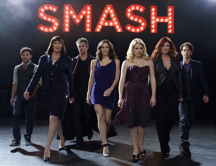 Smash cast posing in front of the Smash logo