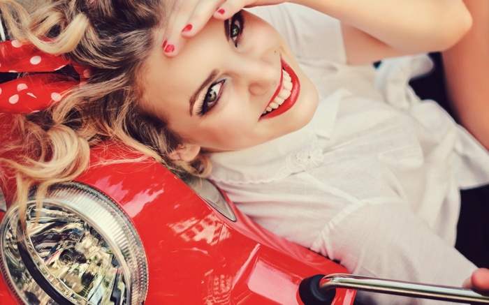Woman with red polka dot headband on a red scooter