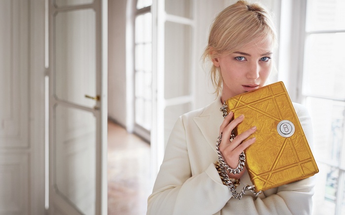 Woman in white blazer holding a gold Dior bag
