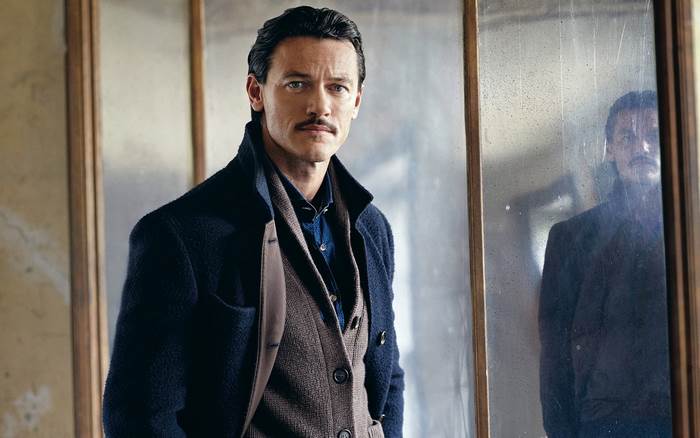 Luke Evans in a dark coat and vest