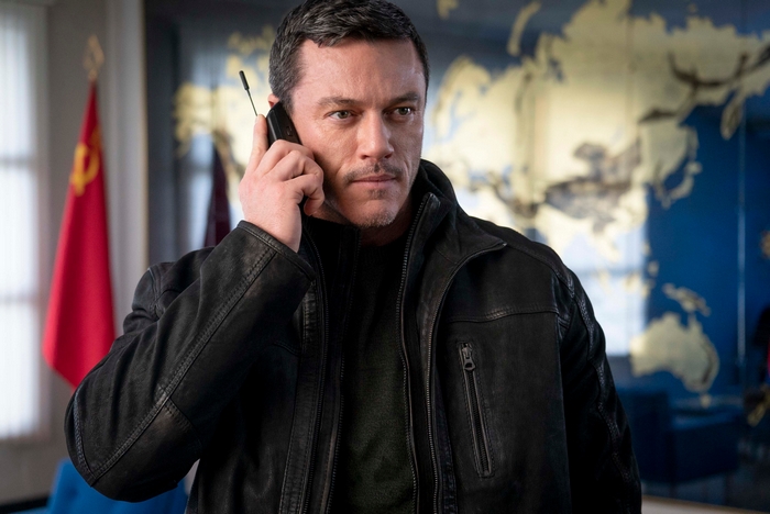 Luke Evans on phone in front of world map