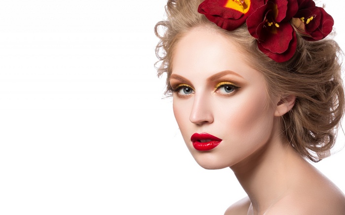 Woman with red flowers in hair and bold makeup