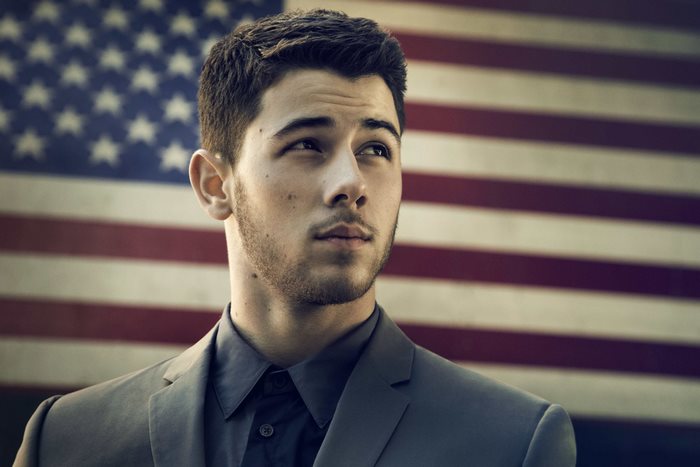 Nick Jonas in front of American flag