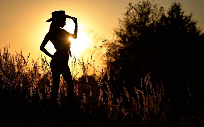 Silhouette of a woman in a cowboy hat at sunset