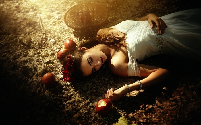Woman in white dress lying on the ground with apples