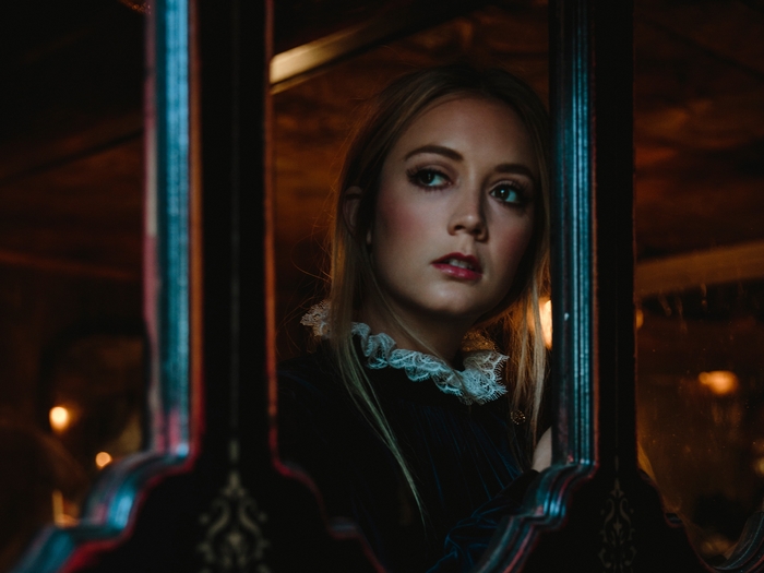 Billie Lourd in a dark, ornate setting
