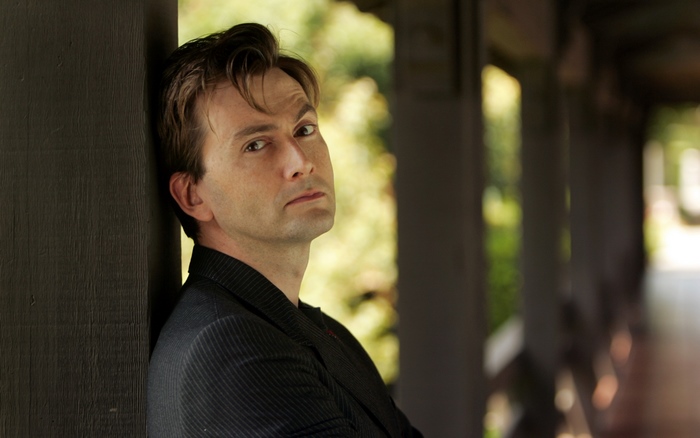 David Tennant leaning against a wooden post