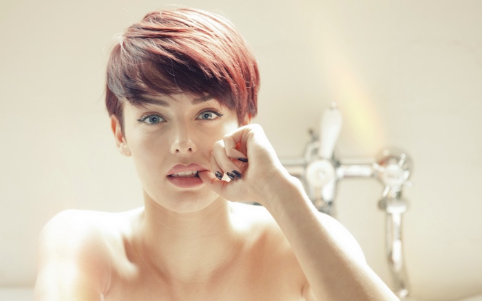 Woman biting her fingernail in a bathroom