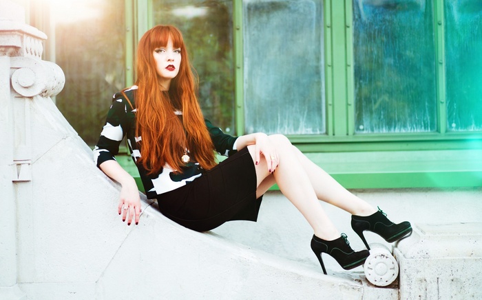 Woman with red hair sitting on a ledge