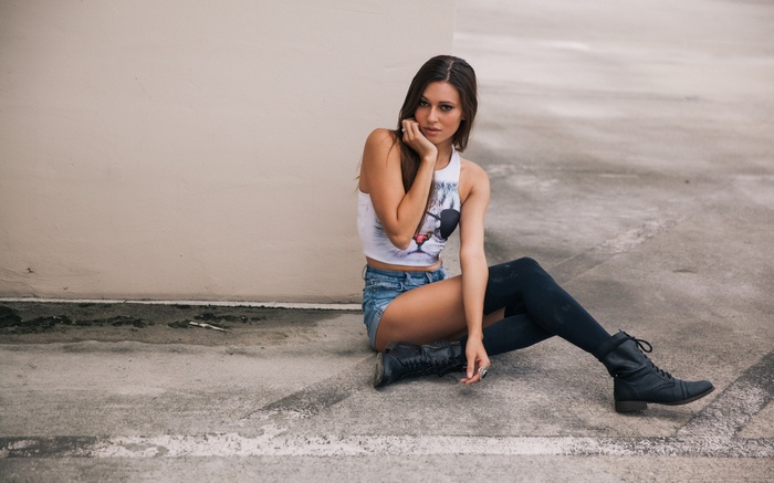 Woman in crop top and shorts sitting on pavement