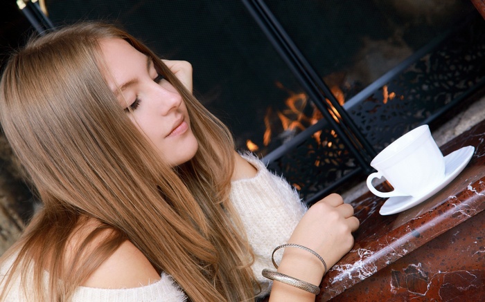 Young woman by a fireplace with a cup of tea