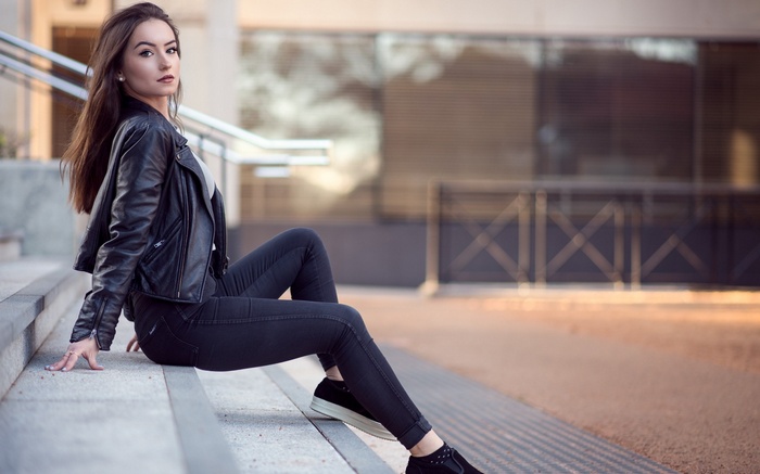 Woman in leather jacket sitting on stairs
