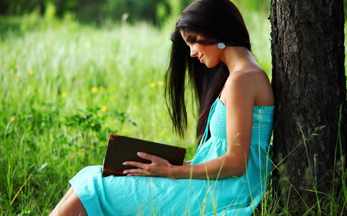 Woman reading a book under a tree