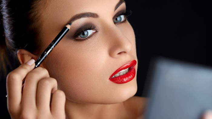Woman applying makeup with eyebrow pencil
