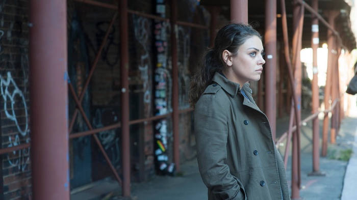 Woman in trench coat standing near graffiti