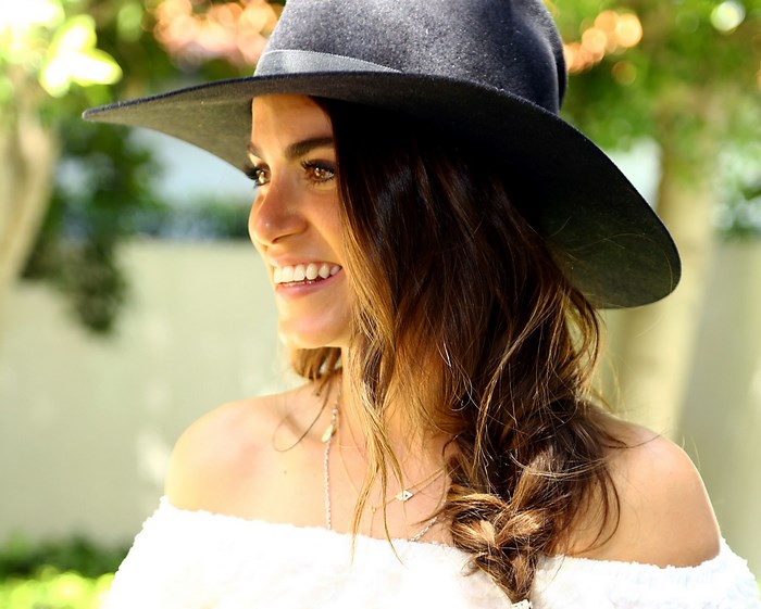 Nikki Reed wearing a black hat and white off-the-shoulder top