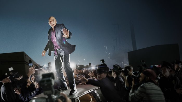 Patrick Stewart on a car surrounded by paparazzi