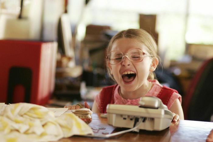 Girl with glasses laughing at a table