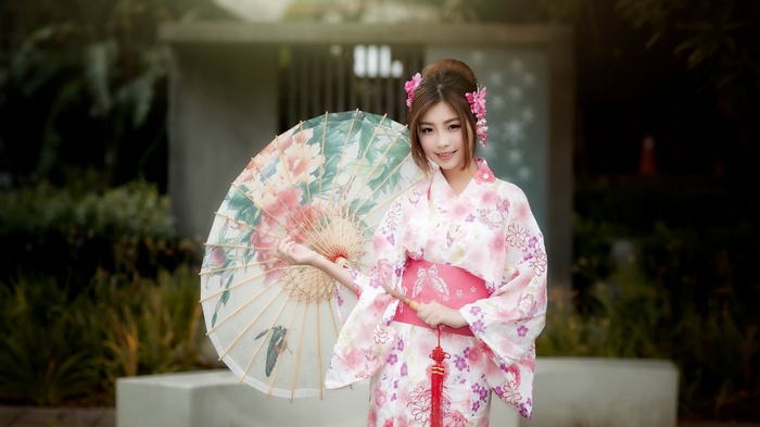 Woman in a pink kimono holding a floral umbrella
