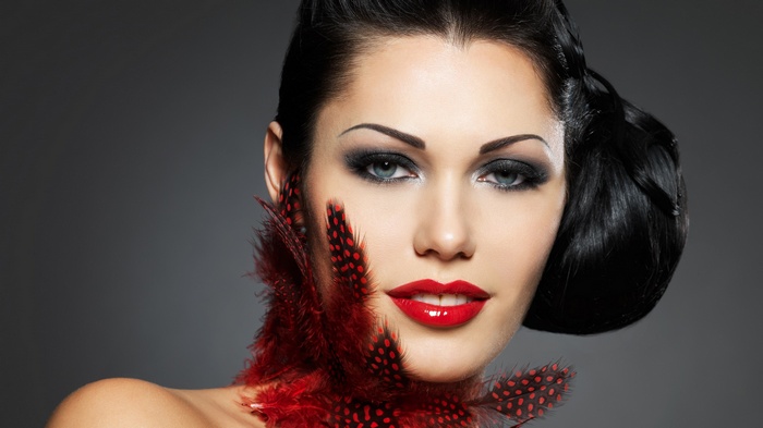 Woman with red feathers and dramatic makeup