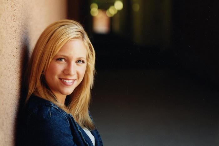 Brittany Snow leaning against a wall