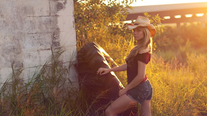 Woman in cowboy hat and denim shorts in a field