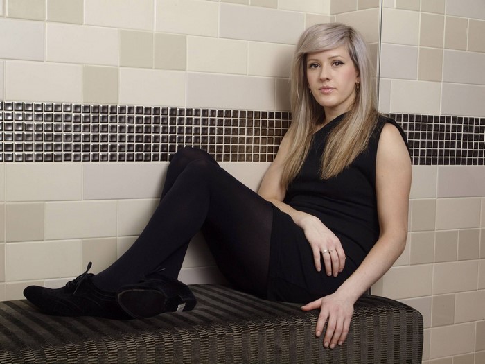 Ellie Goulding sitting on a bench