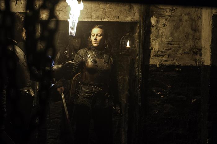 Gemma Whelan in armor holding a torch