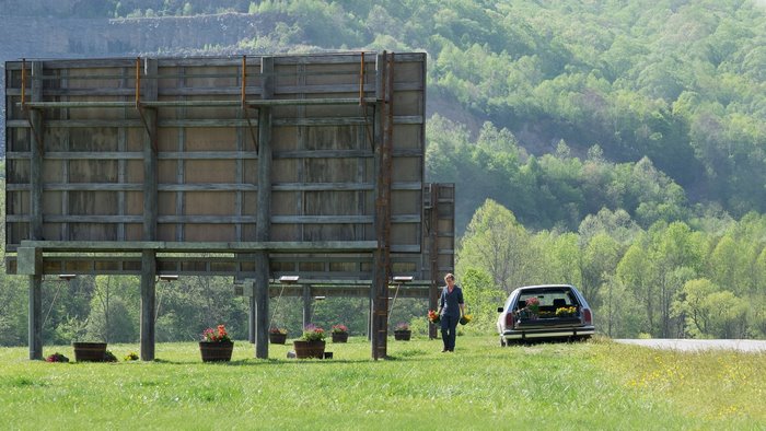 Frances McDormand with flowers near billboards