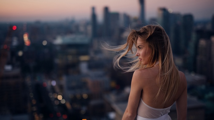Woman on a rooftop overlooking city at dusk