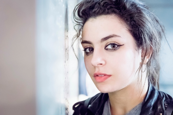 Charli XCX leaning against a wall