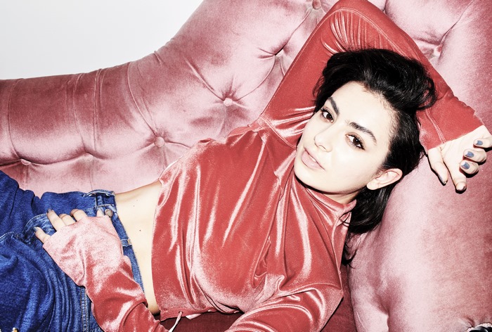 Charli XCX lying on a pink couch