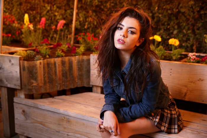 Charli XCX sitting on a bench