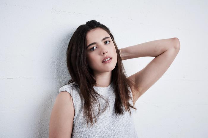 Margaret Qualley leaning against a white wall