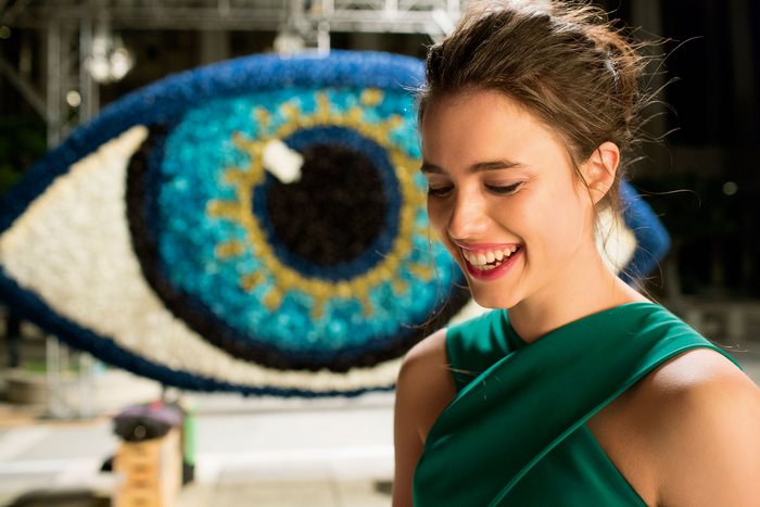 Margaret Qualley in front of a large eye sculpture