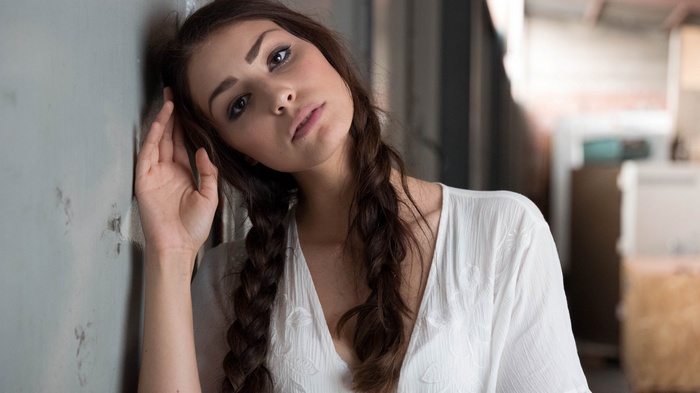 Woman with braided hair leaning against a wall