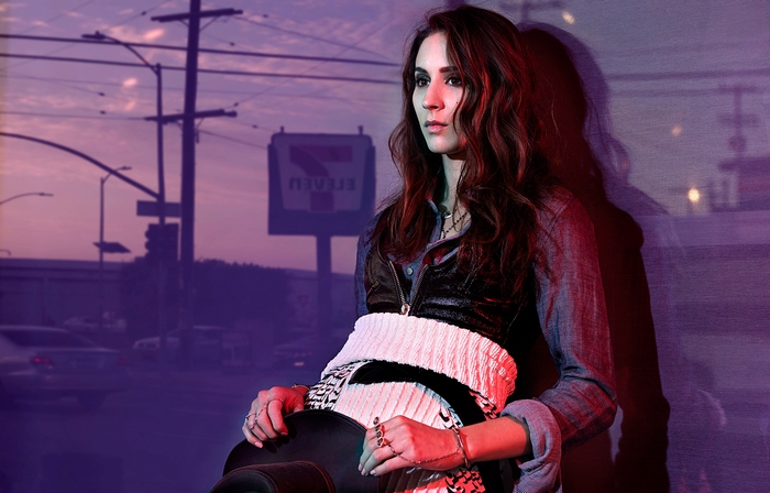 Troian Bellisario sitting in front of a 7-Eleven sign