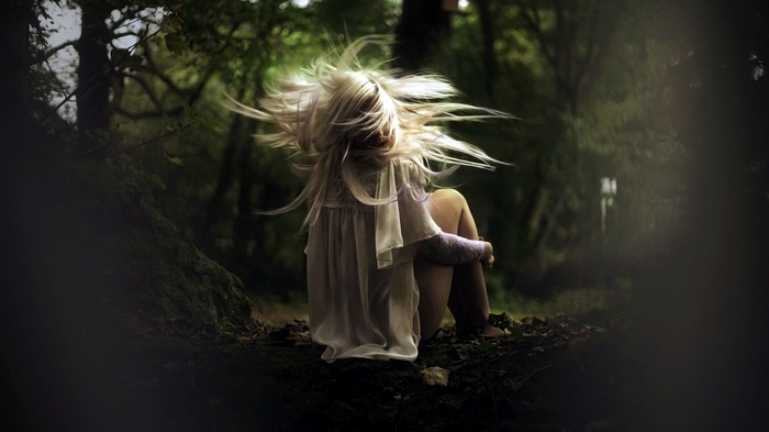 Woman with blonde hair sitting in a forest