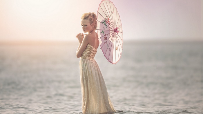 Girl in a dress holding a parasol in the water
