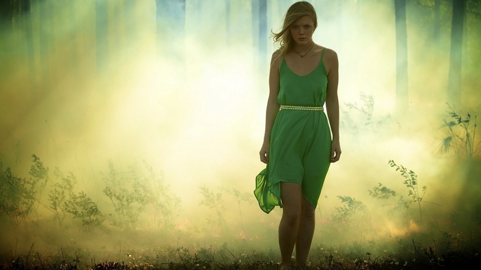 Woman in green dress in smoky forest