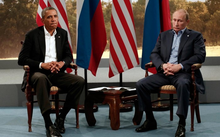 Barack Obama and Vladimir Putin sitting with flags