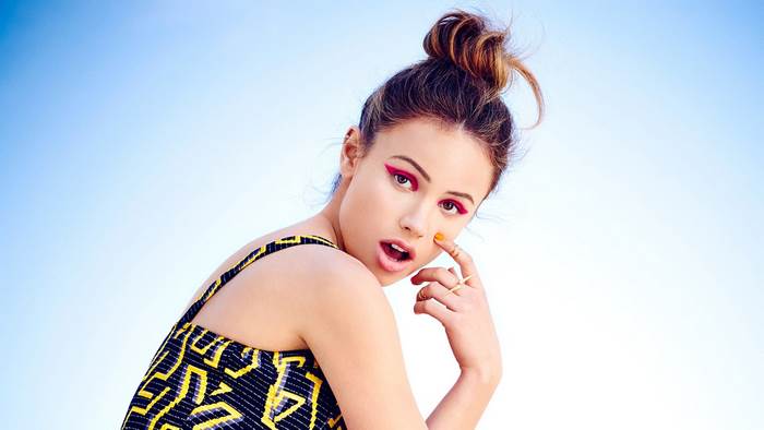 Halston Sage posing against a blue sky