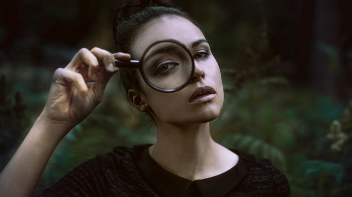 Woman looking through a magnifying glass