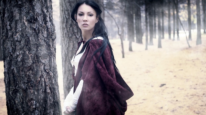 Woman in a red cloak in a forest