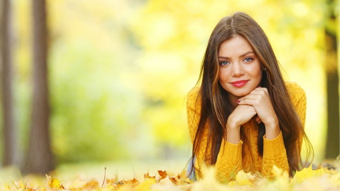 Young woman lying in autumn leaves