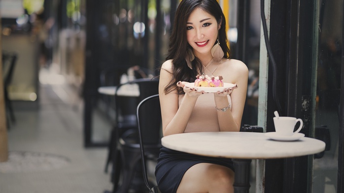 Woman holding a dessert at a cafe table