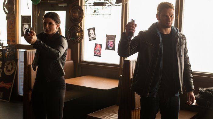 Gina Carano and male actor with guns