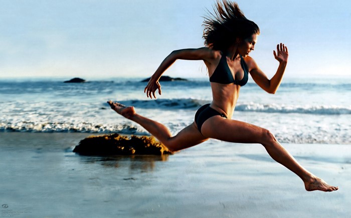 Hilary Swank jumping on a beach